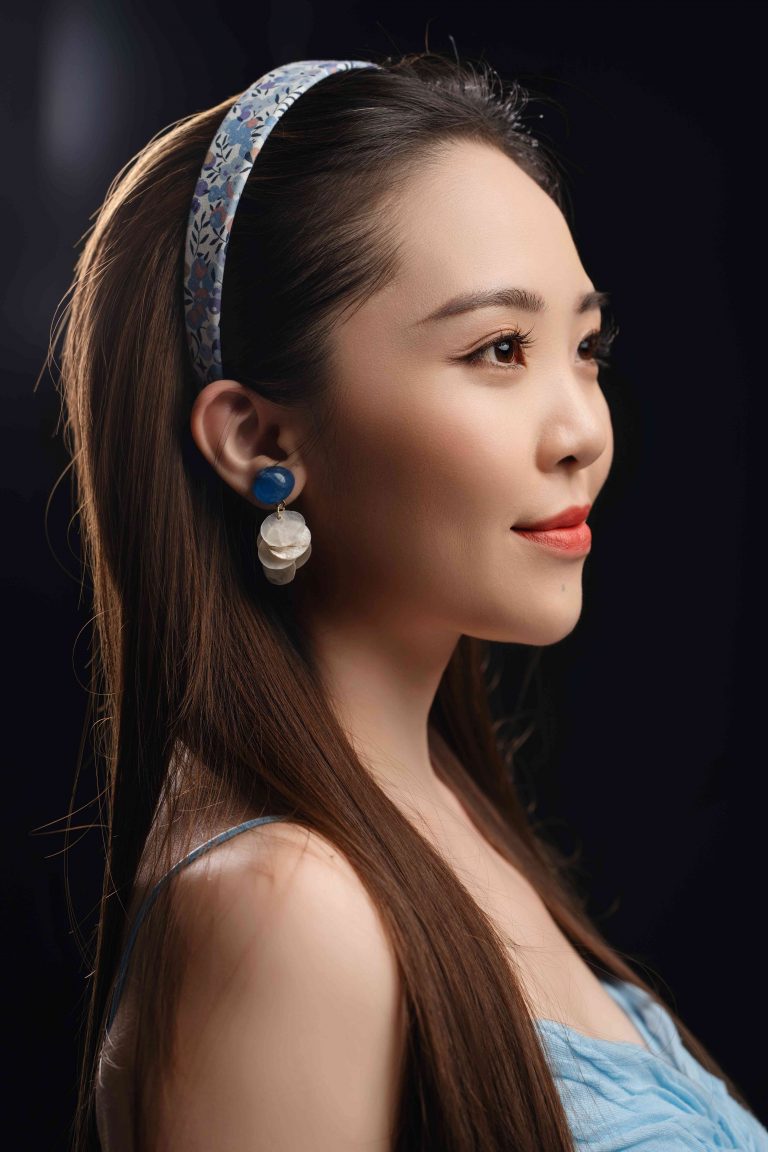 Chụp ảnh beauty phông tối tông ấm: cô gái tóc nâu dài, bờm ngọc trai, áo cúp ngực xanh, nghiêng mặt trong vùng sáng hẹp, thực hiện bởi Lus Photo