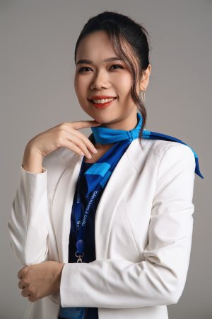 Chụp ảnh chân dung nữ doanh nhân mặc blazer trắng phối khăn lụa xanh quàng cổ, đứng trước phông nền xám sáng, thực hiện bởi Lus Photo