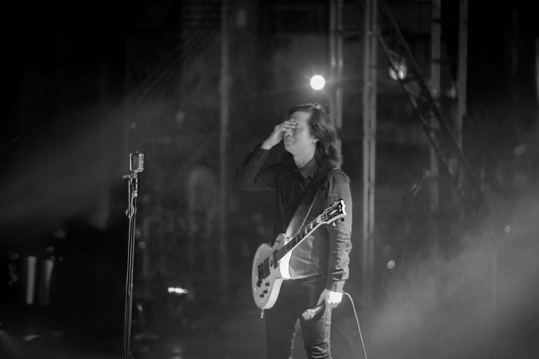 Chụp ảnh rock show trắng đen: tay guitar biểu diễn trên sân khấu trong làn khói, ánh sáng ngược từ dàn đèn phía sau, thực hiện bởi Lus Photo