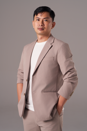 Chụp ảnh chân dung doanh nhân nam mặc vest màu be phối áo thun trắng, hai tay đút túi trên phông nền xám, thực hiện bởi Lus Photo