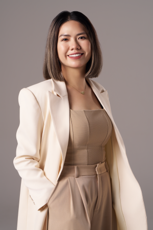 Chụp ảnh chân dung nữ doanh nhân mặc blazer màu kem phối áo corset và quần be, tay đút túi, cười tự nhiên trên phông nền nâu xám, thực hiện bởi Lus Photo