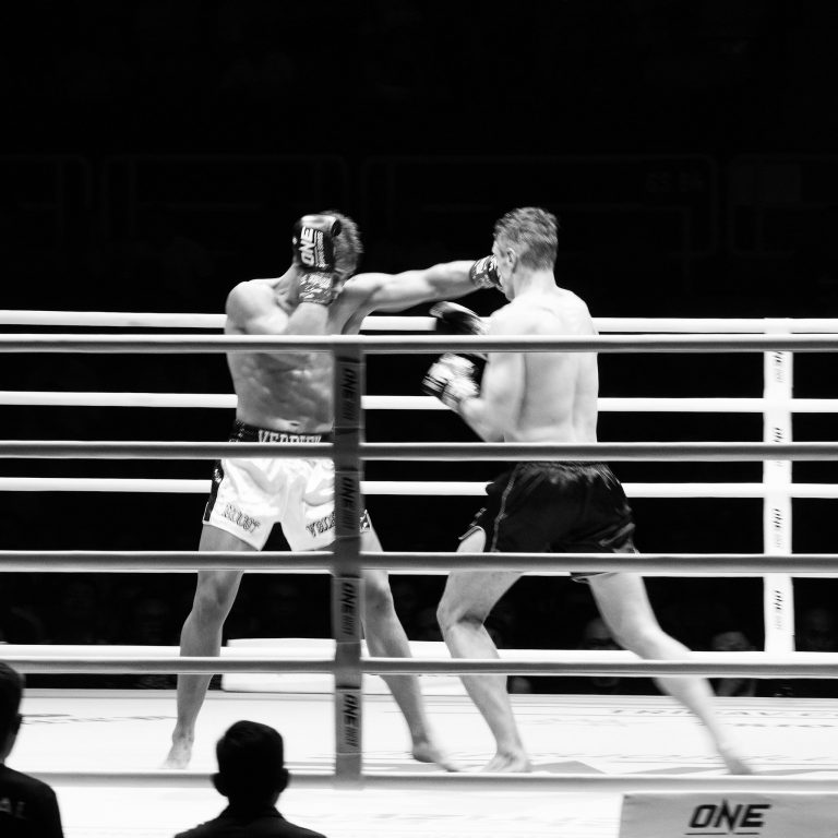 Ảnh giải đấu MMA trắng đen: võ sĩ tung cú đá về phía đối thủ trên võ đài, thực hiện bởi Lus Photo